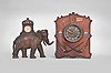 Clocks- 2 (Two): (1) Golden Novelty Mfg. Co., Chicago, elephant novelty clock, 30 hour, time only, spring driven balance wheel movement in a cast iron case shaped like an elephant, c1895; (2) Wm. L. Gilbert Clock Co., Winsted, Conn., "Cosey Corner, Pattern R" cabinet clock, 8 day, time and strike, spring driven movement in burnt wood case with dice, cards, poker chips, and domino designs, c1906.