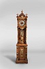 Ansonia Clock Co., New York, New York, "Antique Standing" tall clock, 8 day, time and strike, weight driven movement in an open well oak case with cast brass ornamentation and two brass rope turned weights and brass clad wood end pendulum rod with embossed pendulum bob featuring putti and lion scene. The 10" metal dial has silvered chapter ring, copper center and raised numerals.