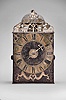 France, Comtoise clock, 8 day, time and strike with alarm, weight driven movement with verge escapement, thread suspension with rear-hanging pendulum in a iron post and plate frame, brass chapter ring with engraved Roman numerals, alarm dial with Arabic numerals, single brass hand, applied brass spandrels and pivoted winding arbor shutters, topped by flat pierced brass fronton with trademark.
