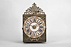 France, month-running Comtoise clock, 30 day, time and strike with alarm, weight driven movement, verge escapement with thread suspension and rear-hanging pendulum in an iron post and plate frame, cast brass dial with inset white enamel cartouche numerals with blue Roman numerals, outer ring with Arabic numerals every five minutes, brass alarm ring with Arabic numerals, two brass hands, applied brass spandrels and pivoted winding arbor shutters, all topped by a pierced brass fronton.