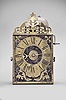 Brocard, Comte, France, Comtoise clock, 8 day, time and alarm, weight driven movement with verge escapement, thread suspension with rear-hanging pendulum in a iron post and plate frame, brass chapter ring with engraved Roman numerals, brass alarm ring with engraved Arabic numerals, flat brass fleur de lis spandrels and pivoted winding arbor shutters, engraved plaque below the dial reading "Brocard en Comte", single pierced brass hand, all topped with a pierced brass fronton.