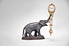 Gebruder Junghans, Schramberg, Germany, elephant model swinging clock, 8 day, time only, spring driven movement with compound pendulum held aloft by a patinated elephant figure on a molded wood base, the clock case with gilt and patinated surfaces, two-tone Arabic numerals on a white enamel dial with the Junghans star trademark and signed "Junghans Germany" below 6:00, two-tone hands.