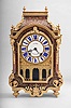 Ourry, a Paris, a large Boulle work and ormolu mounted bracket clock, the case on four turned and flower ringed feet, undulating skirt with conforming bronze mount having a central shell and foliage, arched door with incurved lower corners, and flanked by scroll brackets, foliate drops, and acanthus scrolls, arched cornice molding below a step with corner finials, and surmounted by a removable, cyma curved top, with acanthus corners, floral frieze, and four more urn finials, roman numeral enamel cartouche dial with gilt surround, the enamel center signed "Juhel a Versailles", numbered disc above 12:00 for regulation, and nicely made blued steel pierced and filed hands, above a gilt, architecturally detailed arcaded fret, the rectangular brass movement of at least two week duration with five baluster form pillars, with crown wheel escapement, silk thread suspension, cycloidal cheeks, and count wheel striking, the back plate signed "Ourry a Paris", with large iron key, three partial pendulums, and a 20th century bracket