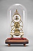 Fournier, a Paris, an early 19th century, month going great wheel skeleton clock, the gilt, inverted Y frames joined by three cylindrical pillars with molded and knurled ends, 6 1/2 inch great wheel with fusee, driven by a large barrel partially concealed in the white marble base, the second wheel concentric with and slightly larger than the Arabic numeral white enamel dial, tic tac escapement with silk thread suspension, blued steel spade hands, and gilt Medusa mask pendulum, the whole resting on ball feet, and under an oval dome with conforming wooden base
