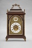 Austria, a late 18th century bracket clock, the molded base with cast, gilt feet, faux arch door with fabric backed frets at the upper corners, and caddy top, surrounded by four finials and with carrying handle, engraved brass dial with roman numeral, white enamel chapter ring, surrounded by cast spandrels, blued steel hands, patterned center with aperture for observation of mock pendulum, and boss in the arch with polychrome enamel scene with bird and basket of flowers, two train, two day movement with crown wheel escapement and rack striking, sounding the hours on a bell