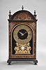 Ourry, a Paris, an ebonized Pendule Religieuse with Boulle work front, the case with molded base and turned feet, case sides with tombstone arch windows, case front with tortoise shell veneers and foliate form brass and pewter inlays, door glass with cast, arched, beaded trim, top with arched, molded tympanum, flanking plinths, and three finials, dial plate lined with deep blue velvet, engraved brass Roman numeral dial with Arabic minutes, fancy cast brass hands, and with cast, gilt brass mount below 6:00, consisting of a balustrade on a molded base supporting foliate ornamented S scrolls, and surmounted by putti, with central enamel cartouche marked "Ourry A Paris", rectangular movement with five baluster form pillars and large barrels, recoil escapement, and counting the hours on a bell, back plate also signed