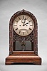 John L. Fenn, a Victorian mahogany table regulator, the arch top case with squat ogee bracket feet and molded base, the door with half round molding with carved leaves and vine, seemingly wrapped around the molding, Roman numeral silvered dial with seconds below 12:00, blued steel hands, and with pierced floral and C scroll carving below, large 8 day fusee movement striking the hours on a coil gong, faux mercury pendulum with heavy brass cylinder fixed horizontally below the jar