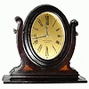 C.1930, Seth Thomas, desk clock, the movement and dial mounted in an oval mahogany frame, the whole setting in a yoke, accented with beechwood inlay.